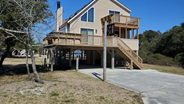 A two-story house with a balcony, a staircase, and a driveway. - Timberland -- 4 BR Oceanside home in Southern Duck (Duck)