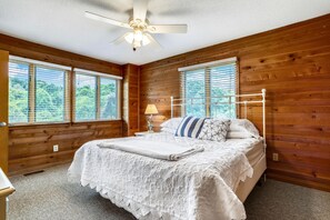Une chambre à coucher avec un lit, une table de chevet, une lampe et un ventilateur de plafond.