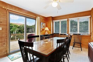 A wooden interior with a dining table, chairs, a ceiling fan, and large windows. - Timberland -- 4 BR Oceanside home in Southern Duck (Duck)