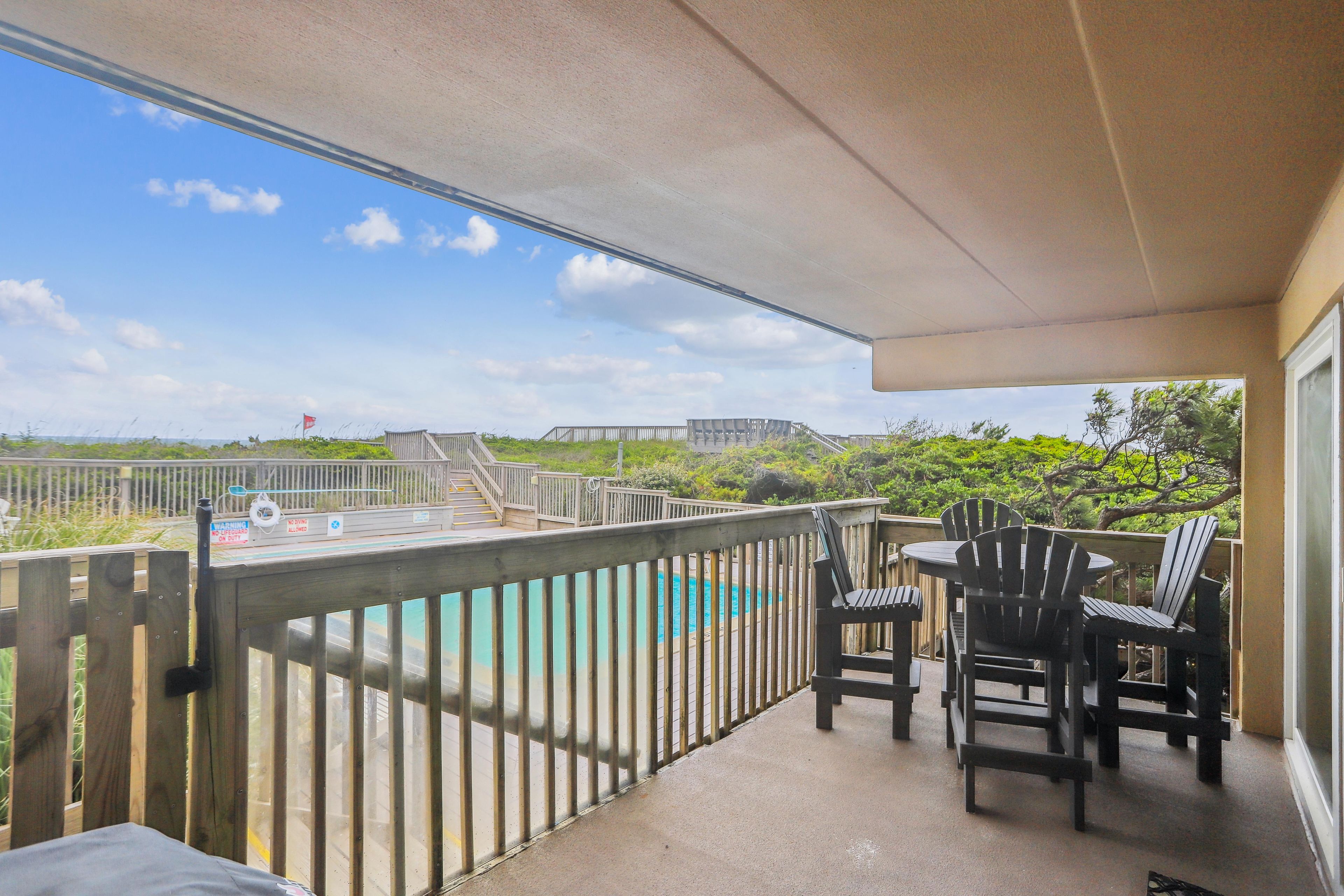 A balcony with a view of a pool and a wooden deck.