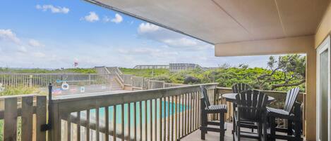 Un balcon avec vue sur une piscine et une terrasse en bois.