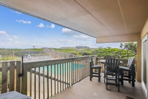 A balcony with a view of a pool and a wooden deck.