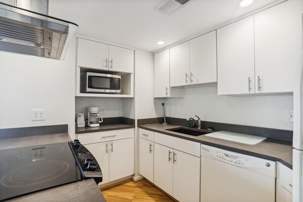A compact kitchen with a built-in microwave, coffee maker, and dishwasher. - The Oceans Unit 301 -- Oceanfront Condo with Direct Access to Pool and Beach (Nags Head)