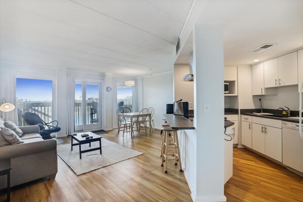 A modern apartment with a dining area, kitchen, and a balcony with a city view.