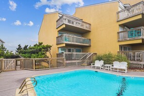 A swimming pool with a wooden deck, white lounge chairs, and a no diving sign. - The Oceans Unit 301 -- Oceanfront Condo with Direct Access to Pool and Beach (Nags Head)