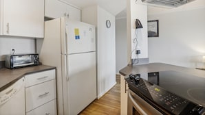 Una cocina con armarios blancos, horno empotrado, microondas y tostadora.