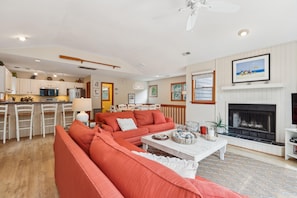A modern living room with a sectional sofa, a fireplace, and a dining area in the background.