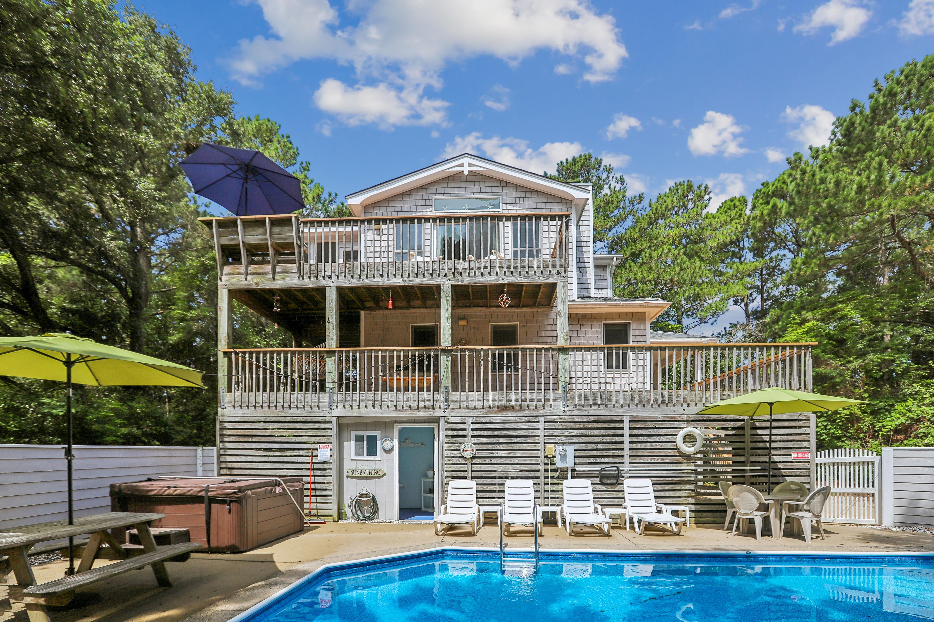 A two-story building with a pool, outdoor seating, and a covered deck area.