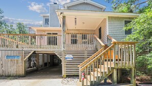 A two-story building with a covered porch and a wooden deck. - Leeward Inn-- Beautifully Decorated Home with Pool, Hot Tub and More! (Southern Shores)