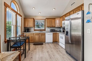 A modern kitchen with wooden cabinets, stainless steel appliances, and a dining area with a glass table and chairs.