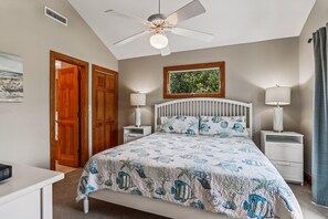 Quarto com cama, duas mesas de cabeceira, ventoinha no teto, janela com vista e uma porta.