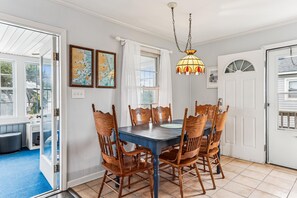 A dining area with a table and chairs, a hanging light fixture, and two framed maps on the wall. - Blankenship Cottage -- Pet Friendly with Sunroom and Just 2 blocks to beach (Nags Head)