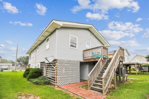 A two-story house with a wooden deck and a staircase leading to a porch.