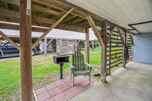A covered outdoor area with a wooden bench, a grill, and a car parked nearby. - Blankenship Cottage -- Pet Friendly with Sunroom and Just 2 blocks to beach (Nags Head)