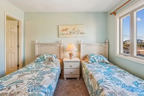 Een slaapkamer met twee bedden, een nachtkastje, een lamp en een schilderij aan de muur.