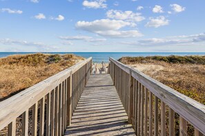 A wooden boardwalk leading to a beach with a clear sky. - Seawalk Unit 8 -- Oceanfront Townhouse with Pool Access (Kill Devil Hills)