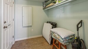 Ein Zimmer mit einem Bett, einem Staubsauger, einem Regal mit gefalteter Kleidung und einer Tür mit dem Schild 'PRIVATE'.