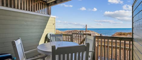 A covered outdoor seating area with a view of the beach and ocean.
