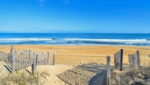 A beach with a wooden fence and the ocean in the background. - Seawalk Unit 8 -- Oceanfront Townhouse with Pool Access (Kill Devil Hills)