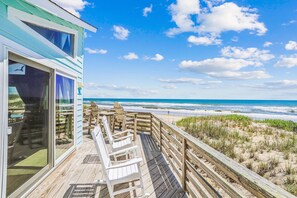 A wooden deck with chairs overlooking a beach and ocean. - Freebird -- Pet Friendly Oceanfront in South Nags Head (Nags Head)