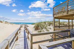 A wooden boardwalk leading to a beach with a wooden structure on the right. - Freebird -- Pet Friendly Oceanfront in South Nags Head (Nags Head)