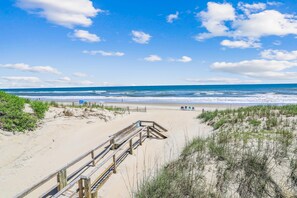 A beach with a wooden boardwalk leading to the shore, sandy dunes, and the ocean. - Freebird -- Pet Friendly Oceanfront in South Nags Head (Nags Head)