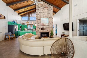 A spacious living room with a large sectional sofa, a fireplace, and a dining area with green cabinets.