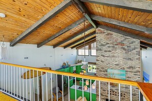 Una habitación con techo de madera, pared de ladrillo y zona de cocina verde.