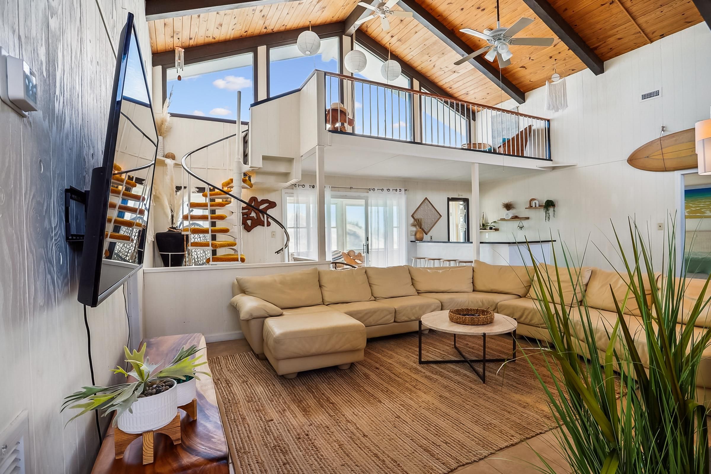 A spacious living area with a large sofa, a coffee table, and a ceiling fan.