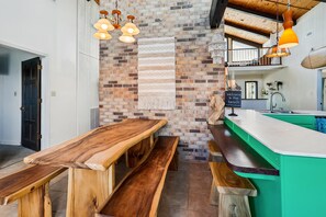 Una cocina con un banco de madera, una lámpara colgante y una pared de ladrillo.