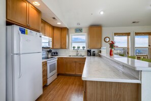 A modern kitchen with wooden cabinets, a white refrigerator, a stove, and a sink. - Miller Cottage -- Semi OF Home in Kitty Hawk with Hot Tub (Kitty Hawk)