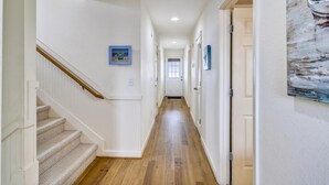 A hallway with a wooden staircase, white walls, and wooden flooring. - Miller Cottage -- Semi OF Home in Kitty Hawk with Hot Tub (Kitty Hawk)