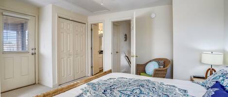 A bedroom with a bed, a ceiling fan, a door, and a chair.