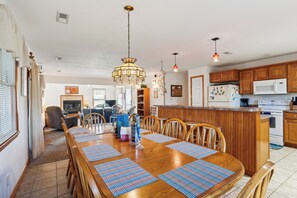 Una cocina amplia con armarios de madera, una isla central y una zona de comedor con una gran mesa y sillas de madera.