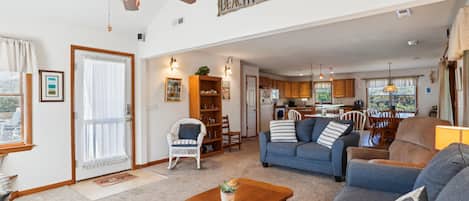 A spacious living room with a ceiling fan, a dining area, and a kitchen with wooden cabinets.