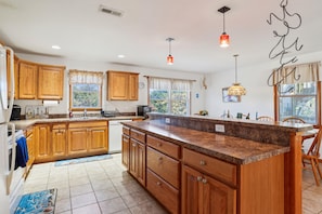 A kitchen with wooden cabinets, a large island, and pendant lighting. - Tax D'Ducktion-- 6BR Oceanside home in Downtown Duck with Pool (Duck)