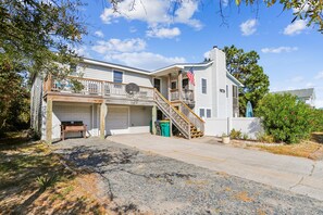 A two-story house with a garage, a covered porch, and a staircase leading to the second floor. - Tax D'Ducktion-- 6BR Oceanside home in Downtown Duck with Pool (Duck)