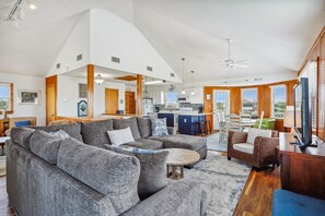 A spacious living area with a sectional sofa, a dining table, and a kitchen in the background.