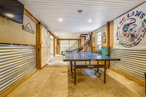 A ping pong table in a room with a high ceiling, wooden beams, and a banner on the wall.
