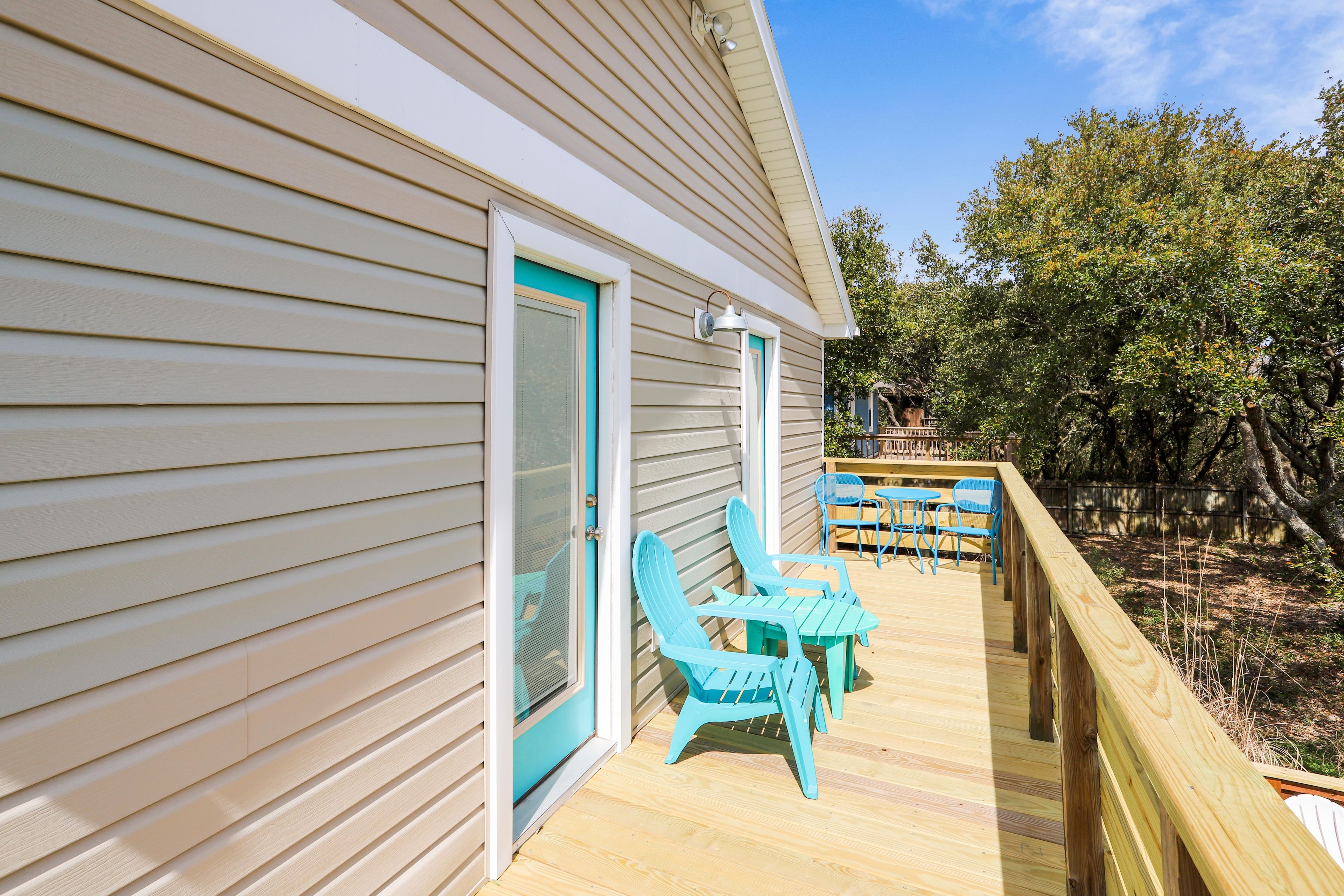A wooden deck with outdoor furniture and a view of a forested area.
