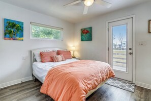 A bedroom with a white bed, orange bedding, a ceiling fan, and artwork on the walls. - Flamingo -- Pet Friendly Home with Private Pool and Gameroom (Nags Head)