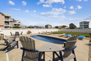 A backyard with a swimming pool, lounge chairs, and a deck. - Paws in the Sand -- Gorgeous Pet Friendly Home with Pool (Kitty Hawk)