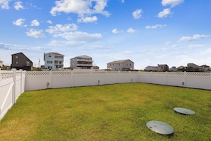 A residential area with a fenced yard, houses, and a clear sky. - Paws in the Sand -- Gorgeous Pet Friendly Home with Pool (Kitty Hawk)