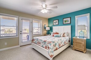 A bedroom with a bed, a nightstand, a ceiling fan, and a window with blinds. - Paws in the Sand -- Gorgeous Pet Friendly Home with Pool (Kitty Hawk)