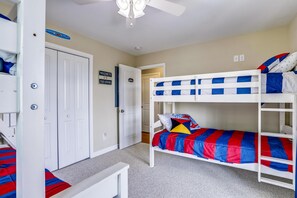 A bunk bed room with a door, a welcome sign, and a ceiling fan.