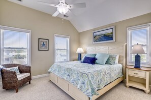 A bedroom with a bed, a chair, a nightstand, and a ceiling fan. - Paws in the Sand -- Gorgeous Pet Friendly Home with Pool (Kitty Hawk)
