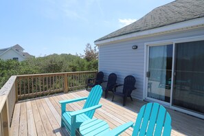 A deck with wooden flooring and two turquoise Adirondack chairs. - Ola Corolla -- Pet Friendly Oceanside home with Pool, Hot Tub (Corolla)