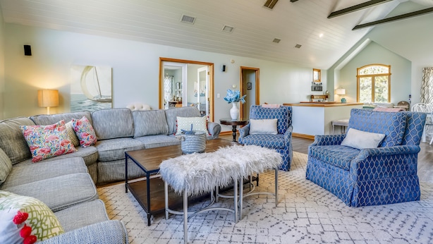 A spacious living room with a sectional sofa, a patterned armchair, and a coffee table. - Ola Corolla -- Pet Friendly Oceanside home with Pool, Hot Tub (Corolla)