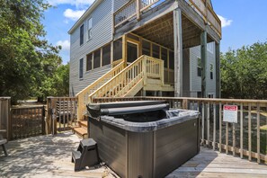 A two-story building with a wooden deck and a hot tub. - Ola Corolla -- Pet Friendly Oceanside home with Pool, Hot Tub (Corolla)