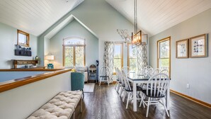 A dining area with a high ceiling, wooden flooring, and a bar area with a cushioned bench. - Ola Corolla -- Pet Friendly Oceanside home with Pool, Hot Tub (Corolla)